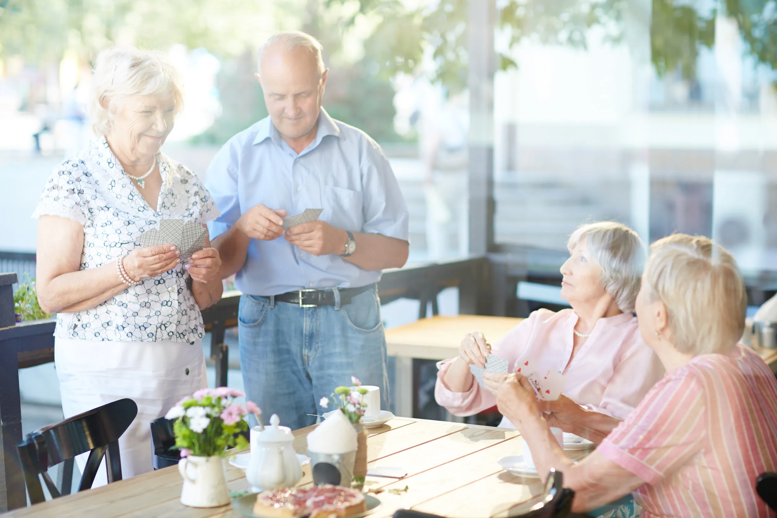 Group of seniors playing cards in outdoor cafe